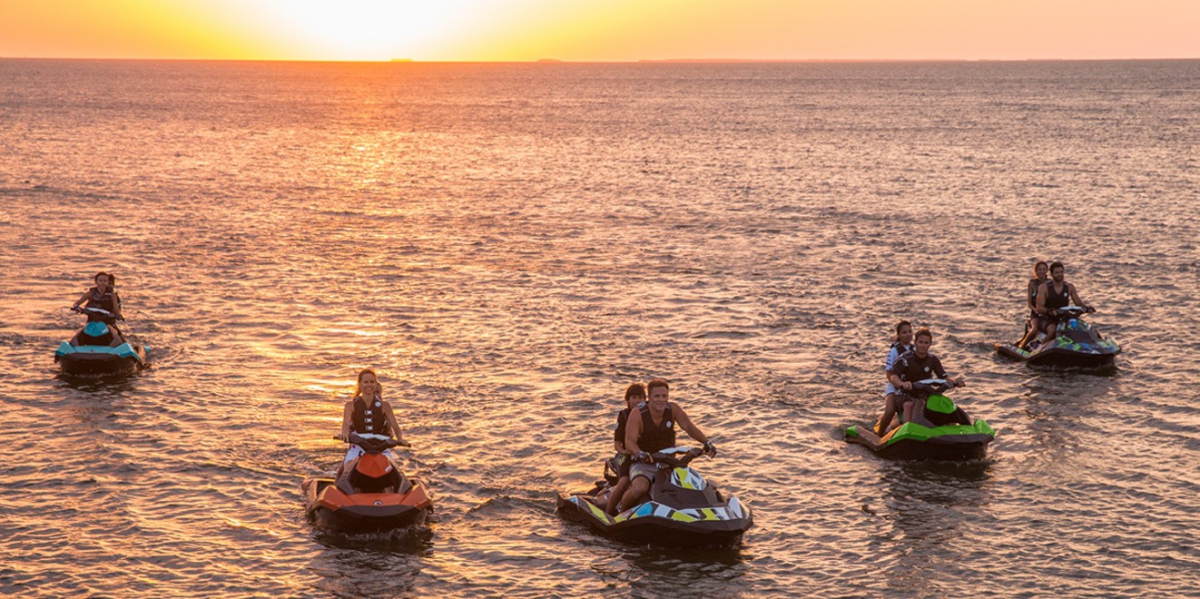 Group of jet skiers riding at sunset